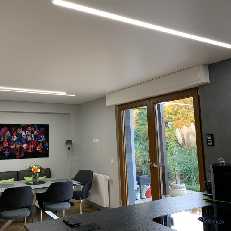 Spanndecke mit Lichtlinien in einer Küche über der Arbeitsfläche und dem Essbereich